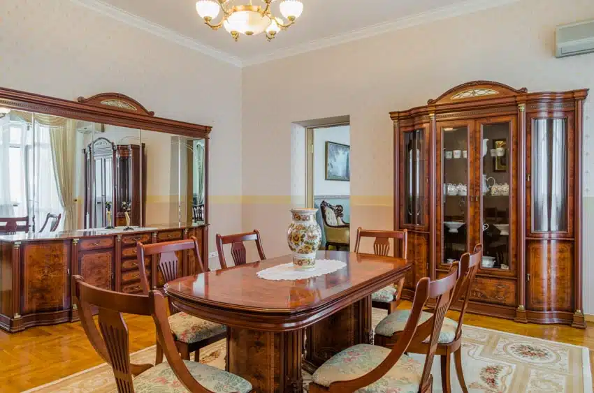 Classic dining room with tiger maple wood table, glass cabinet, chairs, mirror, rug, and chandelier