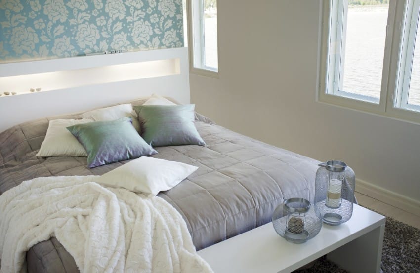 Floral wall accent, comfortable bed with cushion and blanket and a bench with lamps in a cottage style bedroom