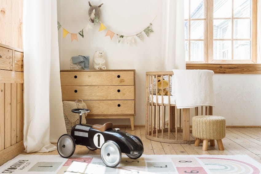 Comfortable kid bedroom in bohemian interior style with home decor alder wood chest of drawers retro car toy and cozy sleeping baby place