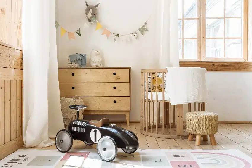 Comfortable kids bedroom in bohemian interior style with home decor alder chest of drawers retro car toy and cozy sleeping baby place