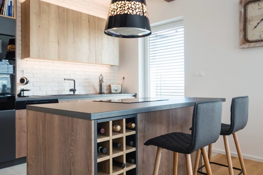 Contemporary kitchen interior features island with formica countertops, wine storage and wooden floors and cabinets