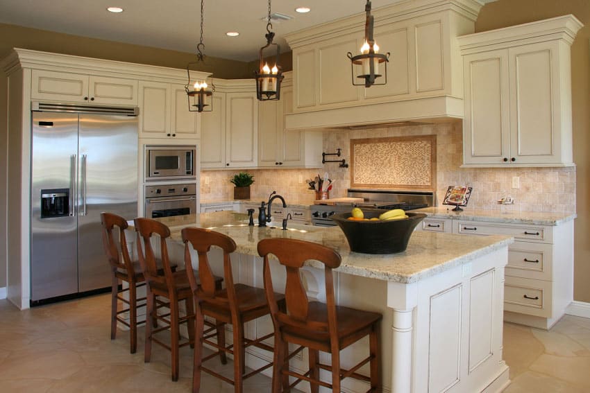 Contemporary kitchen with island, chairs, white cabinets, rubbed oil bronze pendant lights, refrigerator, backsplash, and countertops