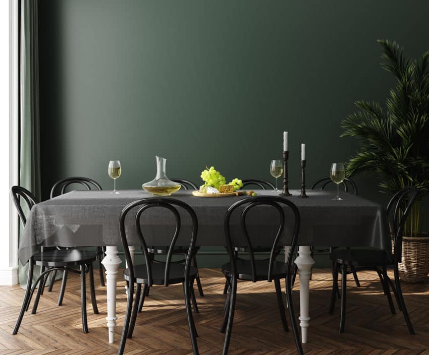 Dining room with dark green paint, dining table, chairs, wood floors, indoor plant, and window curtain