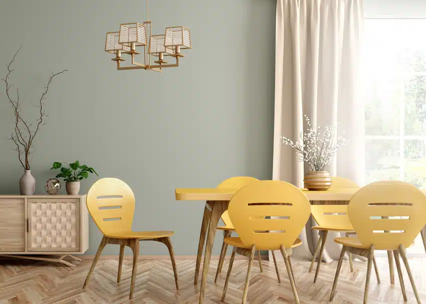 Dining room with light green paint, yellow chairs, table, buffet table, wood flooring, chandelier, and curtains