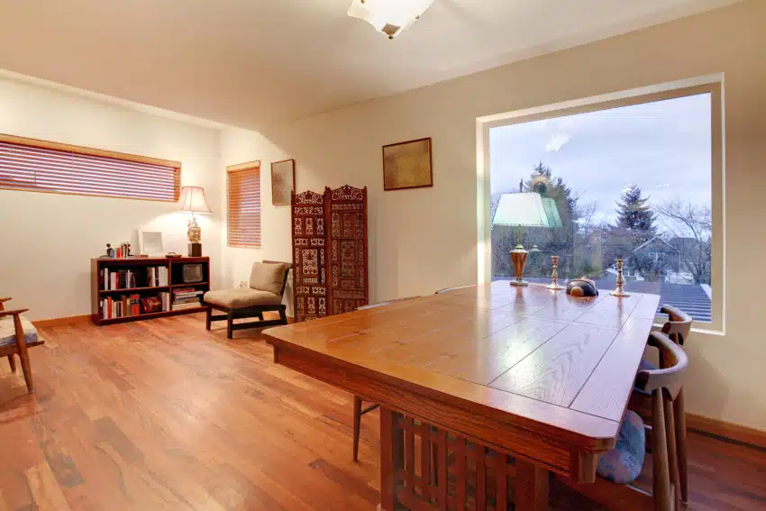 Dining room with mahogany table, wood floors, chair, bookshelf, and window