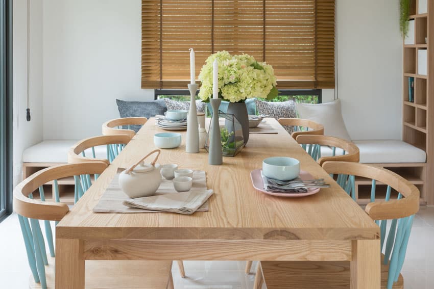 Dining room with oak table, chairs, plates, bench, and wood blinds