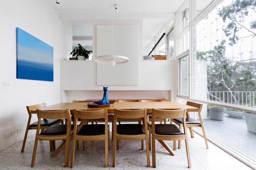 Dining room with oak wood table, chairs, tile floors, pendant lights, and large windows