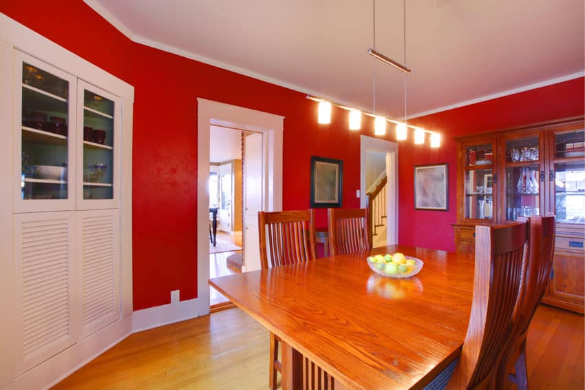 Dining room with red painted walls, mahogany table, chairs, pendant lights, and wood floors