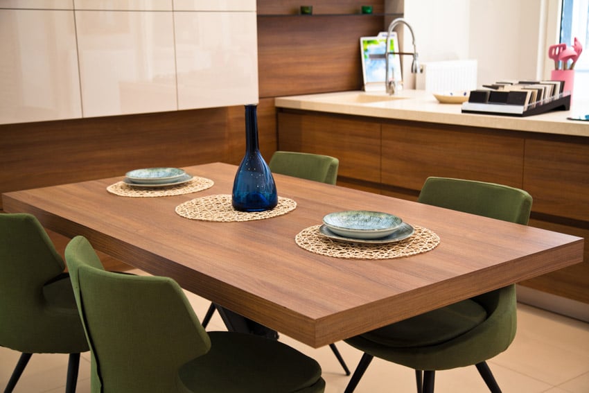 Dining room with walnut wood table, green chairs, cabinets, bar counter, sink, and faucet
