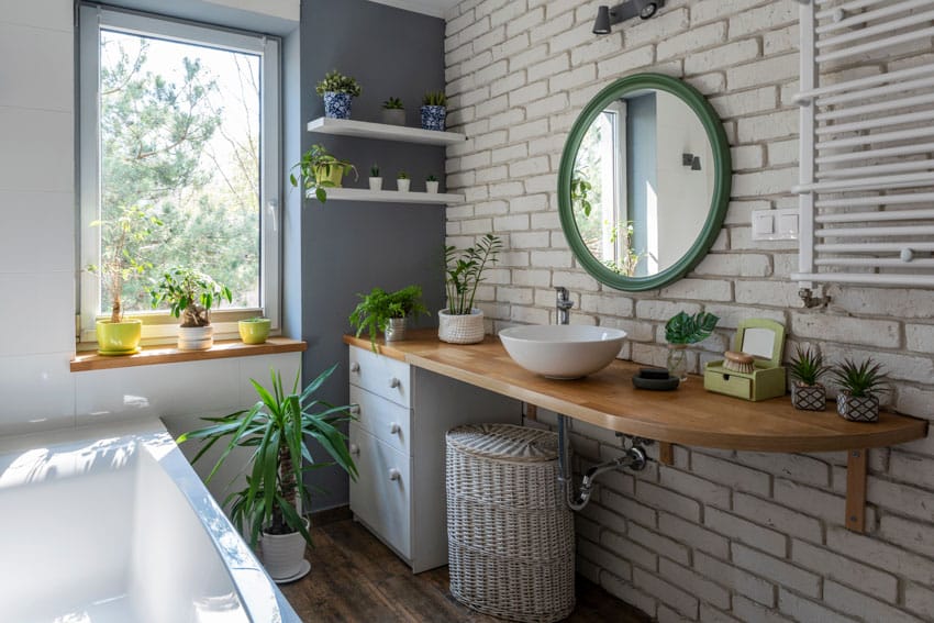 Farmhouse bathroom with crank window, floating wood vanity, sink, mirror, brick wall, and tub