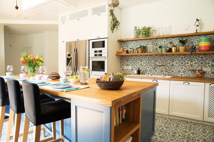 Farmhouse kitchen with Mediterranean style backsplash, floating shelves, oven, and high chairs