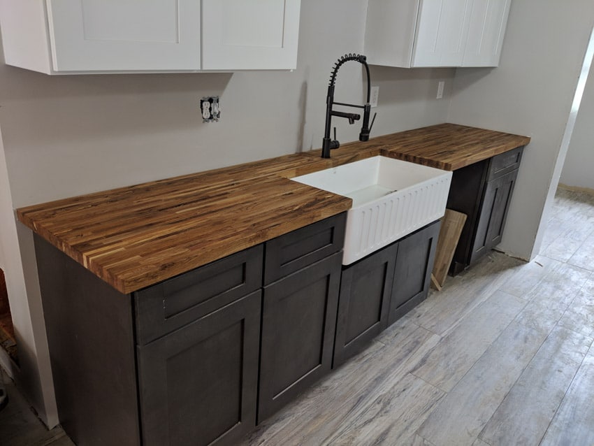 Farmhouse kitchen with edge grain teak wood countertop, farmhouse sink, and cabinets