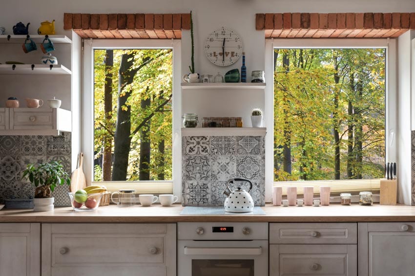 Farmhouse kitchen with handmade Spanish tile backsplash, wood countertop, floating shelves, oven, stove, and windows