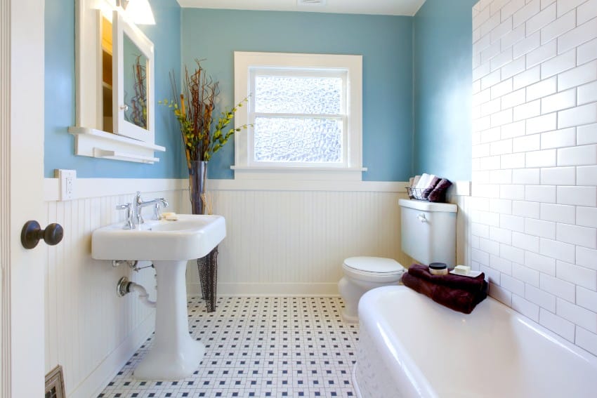 Fresh looking bathroom with white and blue tones features subway tiles on the wall, bathtub and narrow pedestal sink