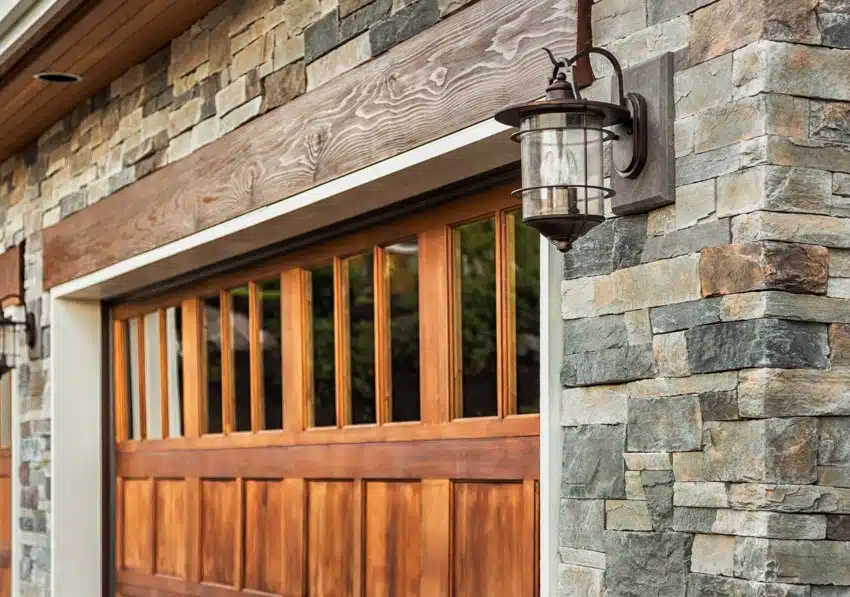 Garage with stone wall cladding, window tint insert, and wall sconce