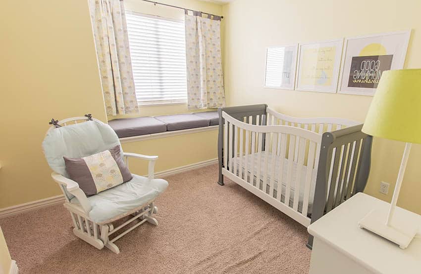 Glider chair in yellow baby nursery room