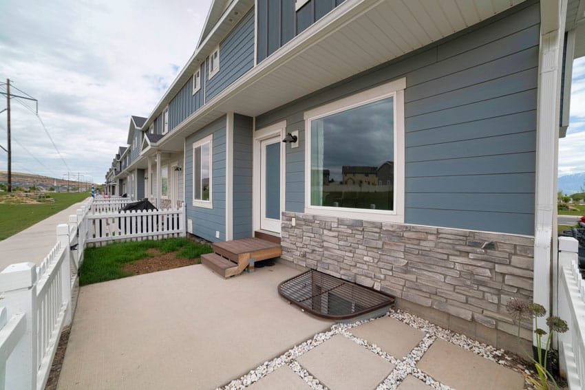 House exterior with blue siding, windows, stone wall, cladding, and security bars for basement windows