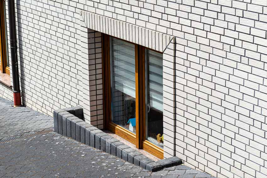 House exterior with brick wall cladding and basement window