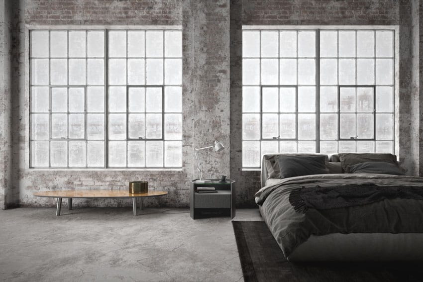 Industrial bedroom with glass windows, wood table, nightstand, comforter, and pillows