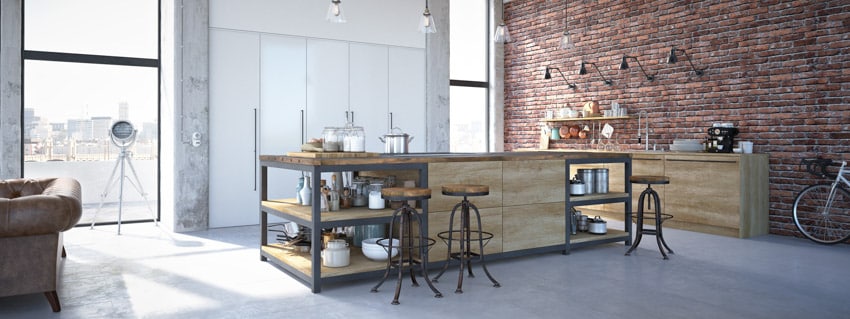 Industrial kitchen with brick wall, island, wood cabinets, bar stools, pendant lights, and windows