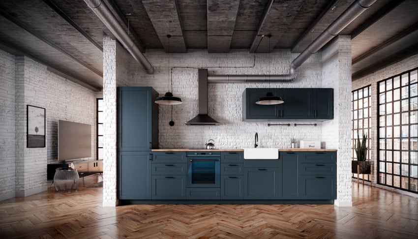 Industrial kitchen with wood floors, cabinets, sink, oven, countertop, concrete ceiling, exposed metal pipes, and windows