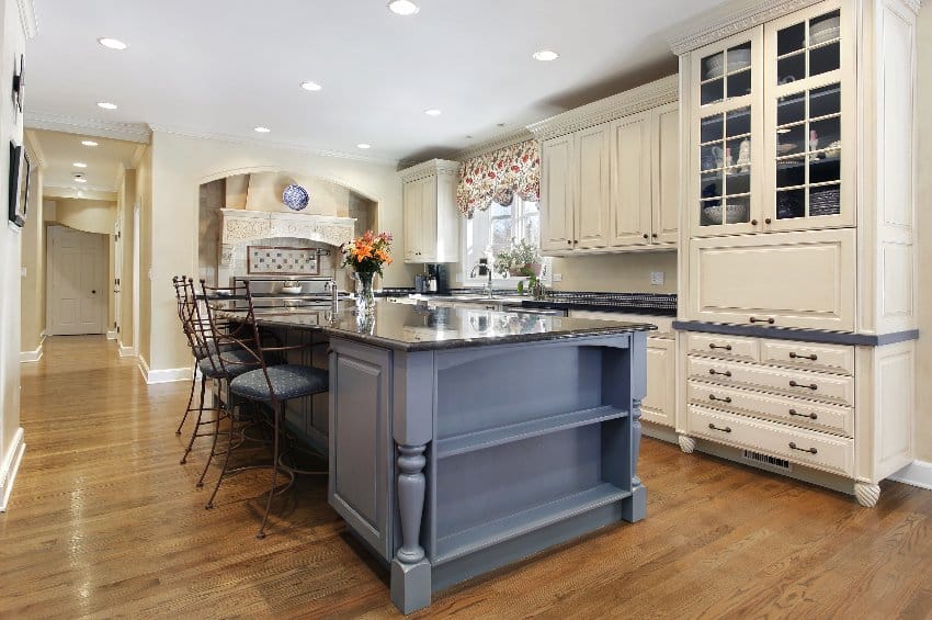 Traditional kitchen with a gray cabinet granite island, hardwood floors and white kitchen cabinets with wood legs