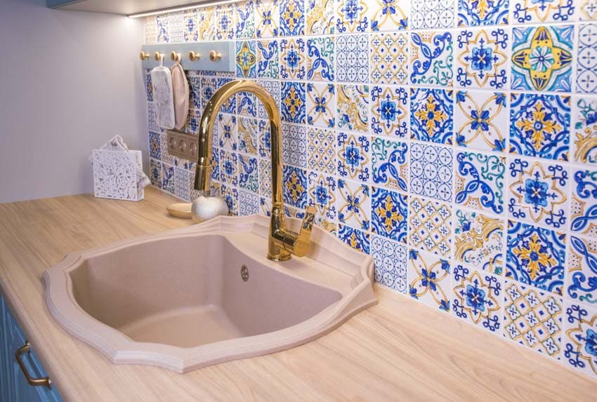 Kitchen with colorful intricate tile and gold faucet