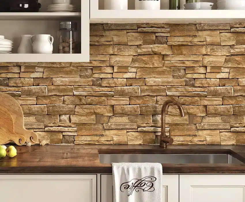 Kitchen with peel and stick stacked stone backsplash, cabinets, countertop, sink, and faucet