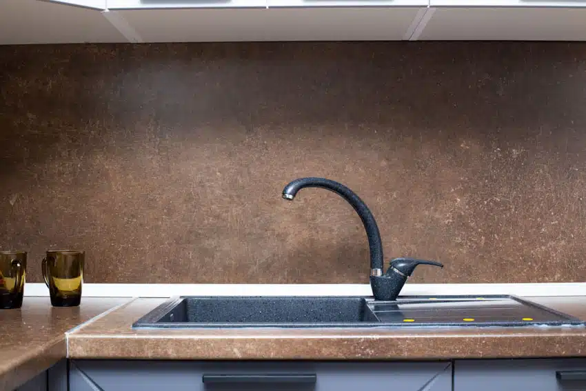Kitchen with sink, faucet, countertop, and laminate backsplash