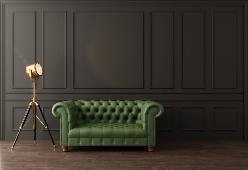 Couch in green leather set with metallic box lamp and dark matte walls