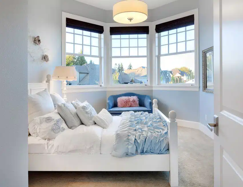 Light blue bedroom with white furniture and bay window