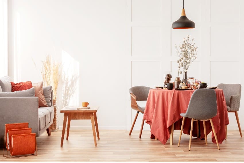 Living and dining room interior with grey couch and table covered with red orange polyester tablecloth