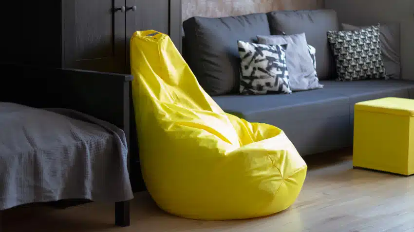 Yellow chair with printed cushions and dark blue sofa