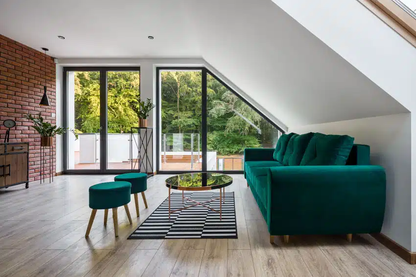Emerald green furniture set, wood flooring, sloped ceiling, brick wall, and glass doors