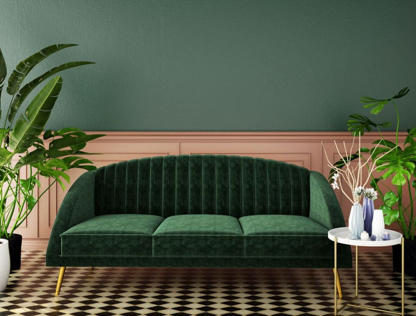 Living room with forest green couch, patterned floor, indoor plants, and small round table