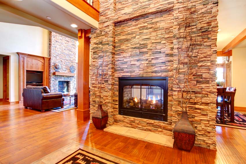 Room with orange column, fire0place with stacked stone accent and rug
