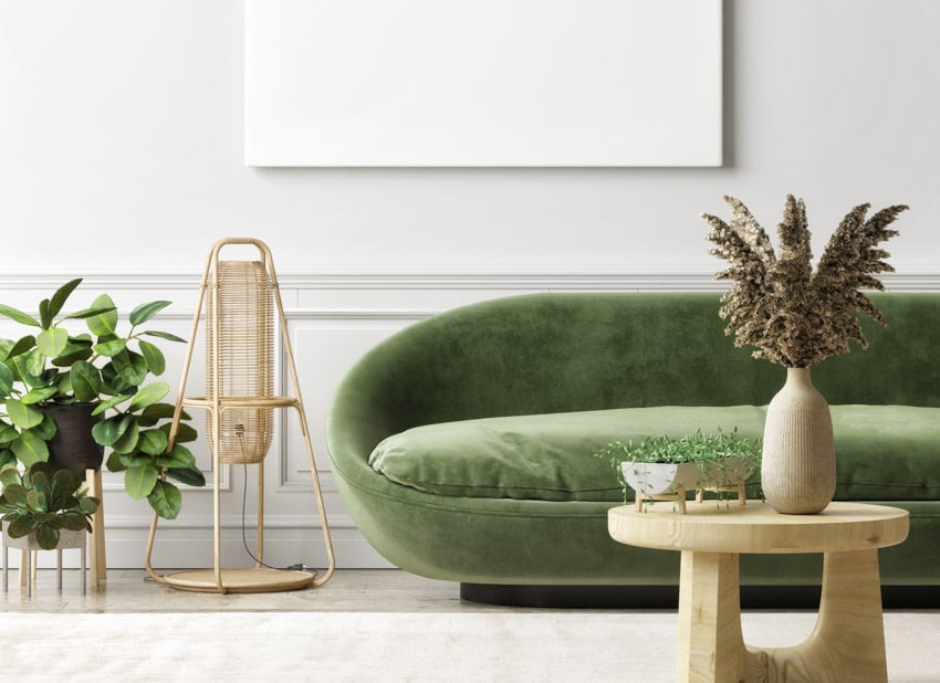 Living room with moss green couch, wood coffee table, vase, and indoor plant