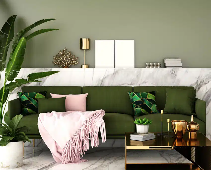 Olive couch with pink throw pillows and marble half wall and flooring