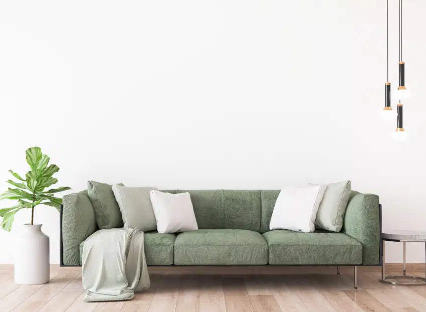 Couch in sage green, white pillows and pendant lights on the side