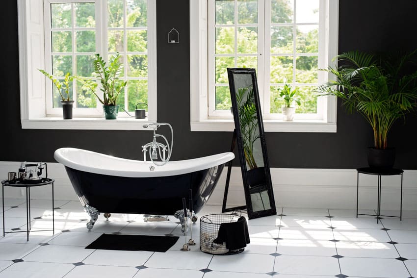 Luxury bathroom with bathtub, tile floors, indoor plant, mirror, windows, and bathtub faucet