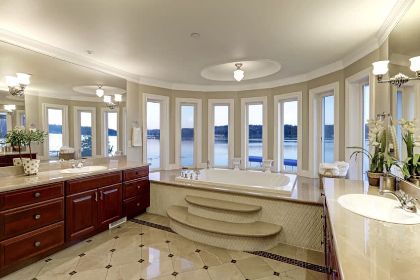 Luxury bathroom with bay windows, tub, tile floor, mirror, cabinets, countertop, sink, and ceiling lights