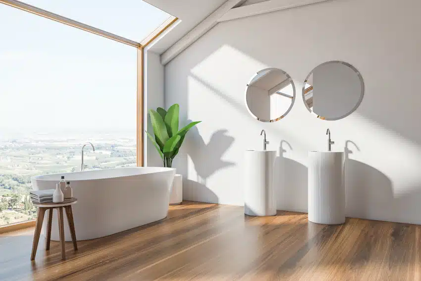 Luxury bathroom with wood floor, sink, mirrors, tub, stool, window, and bathtub faucet