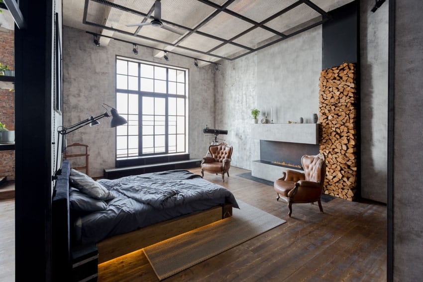 Luxury industrial bedroom with decor pieces, wood accent wall, bed, wooden floors, chairs, floor lamp, and windows