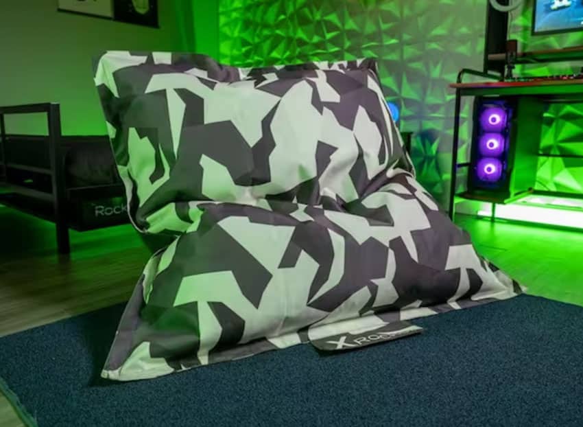 Man cave with gaming bean bag chair, green lighting fixtures, rug, and entertainment system