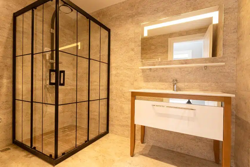 Minimalist bathroom interior features sink with cabinet, mirror and shower with vinyl walls