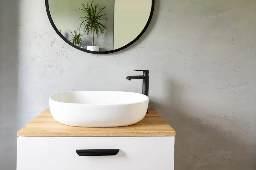 Minimalist bathroom with rubberwood butcher block countertop, sink, faucet, and mirror