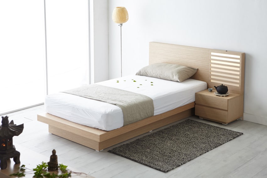 Minimalist bedroom with birch wood headboard, nightstand, mattress, pillows, floor lamp, and glass window