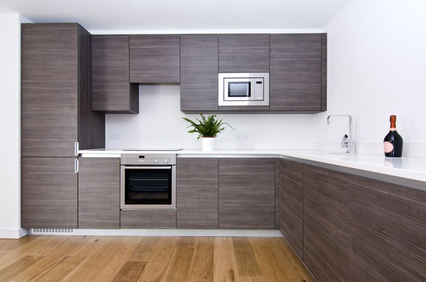 Minimalist kitchen with laminate cabinets, oven, stove, white countertop, and wood floors