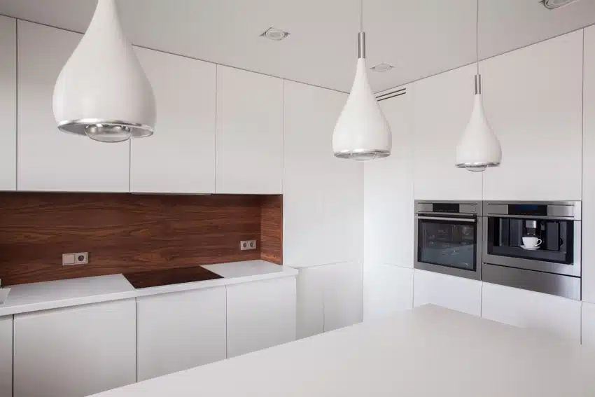 Minimalist kitchen with white cabinets, laminate backsplash, countertop, induction stove, and pendant lights