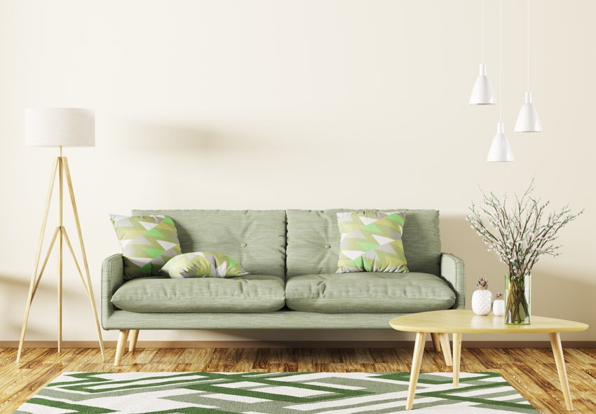 Minimalist living room with light green couch, coffee table, floor lamp, rug, and pendant light